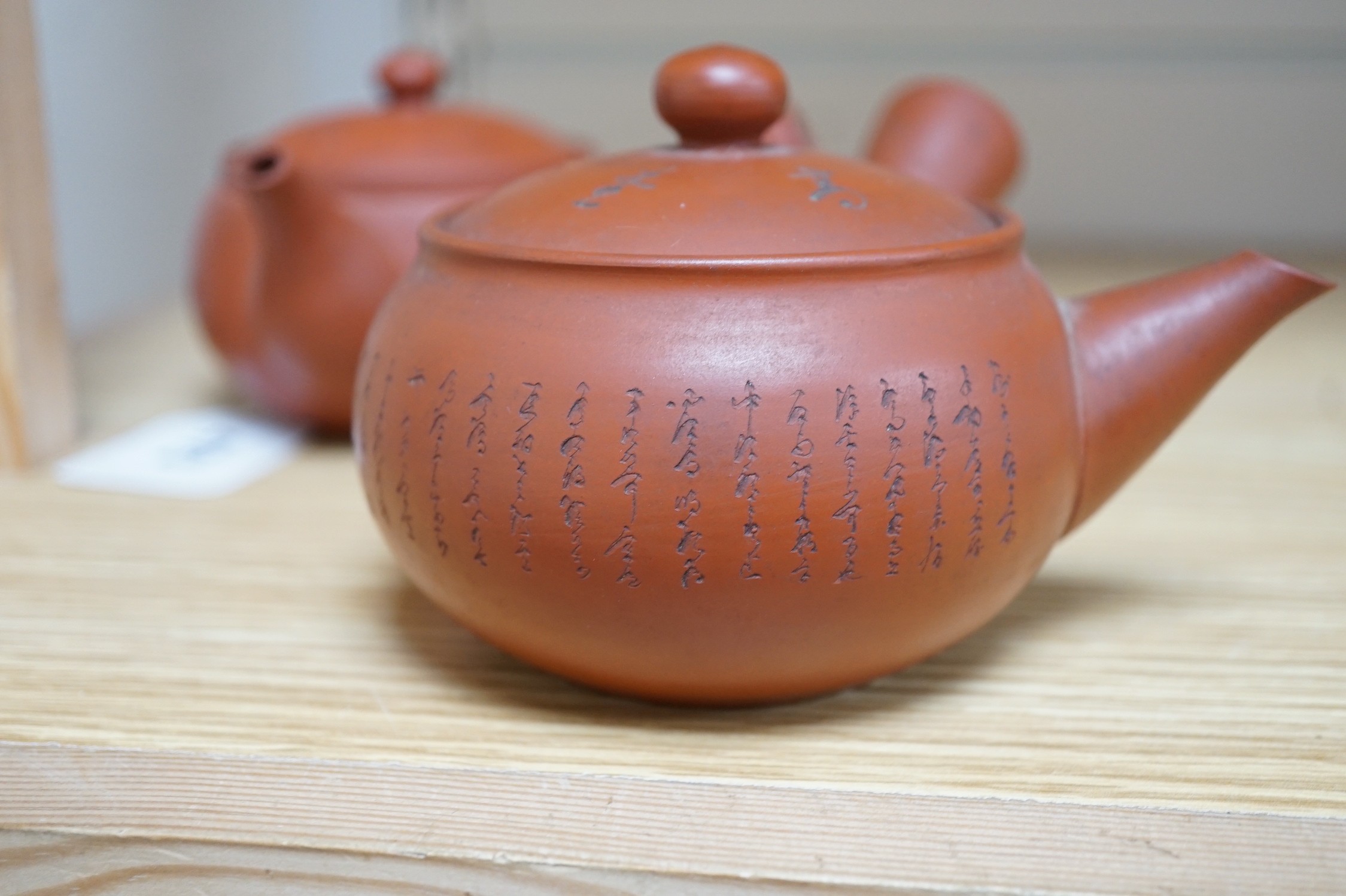 Two Japanese redware teapots, a similar brown stoneware teapot and two cups